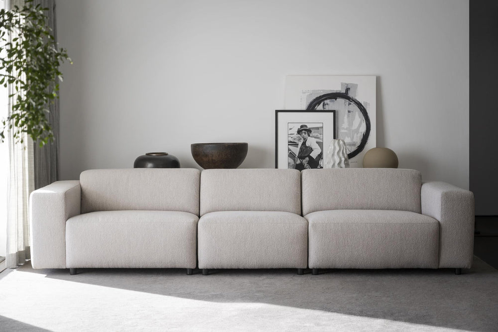 Beige tresitsig modulsoffa med låga armstöd och mjuka kuddar i modern design