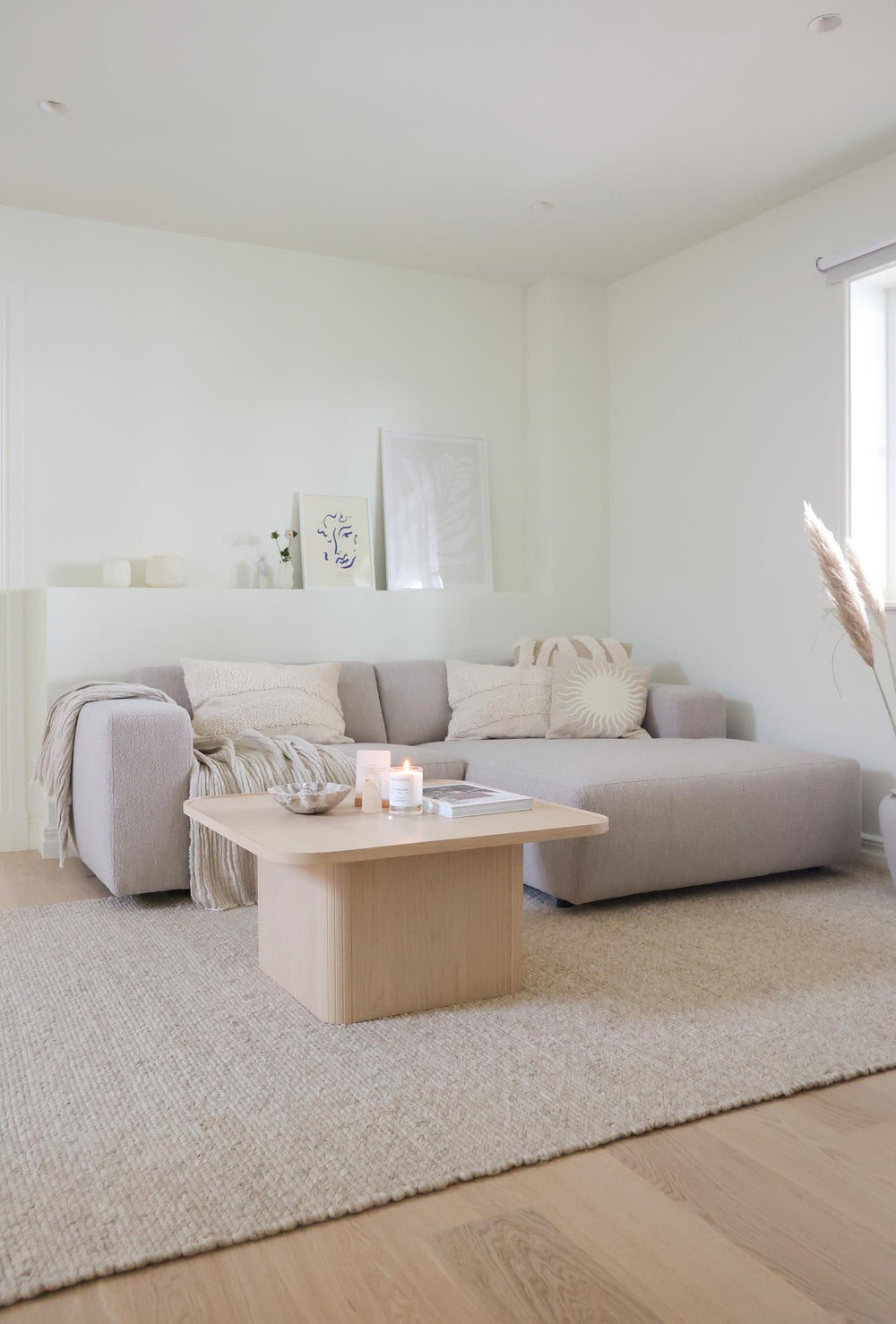 Beige modulsoffa med schäslong i bouclétyg, moderna låga armstöd och svarta träben