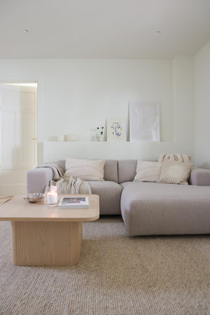 Ljust vardagsrum med beige modulsoffa, träsoffbord och neutral inredning i skandinavisk stil