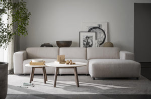 Beige modulsoffa med ottoman och vita soffbord i skandinavisk vardagsrumsinredning