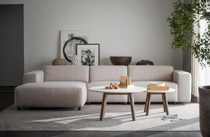 Beige soffa med schäslong och två runda soffbord i skandinavisk design i modernt vardagsrum