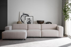 Beige modulsoffa med schäslong i modernt vardagsrum med konstföremål och växter