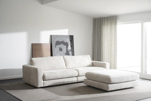 Vit modulsoffa med fotpall i ljust vardagsrum med minimalistisk inredning