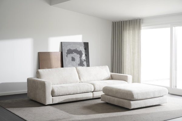 Vit modulsoffa med fotpall i ljust vardagsrum med minimalistisk inredning