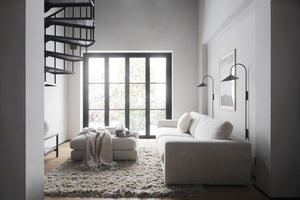 Minimalistiskt vardagsrum med grå soffa, spiraltrappa och stort fönster i industriell stil