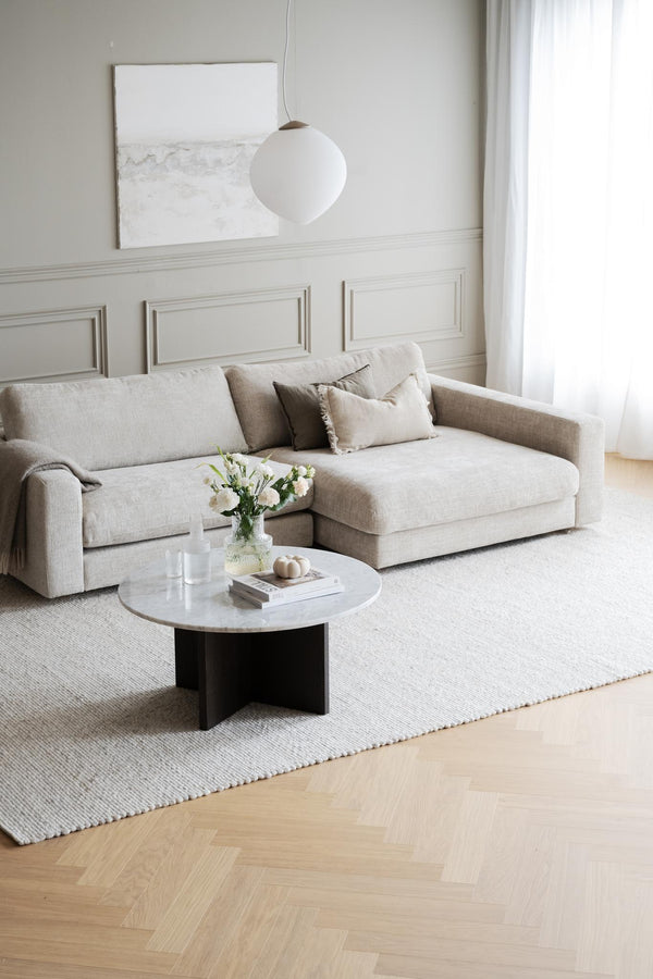 Ljust vardagsrum med beige modulsoffa, runt marmorbord och vit klotlampa i minimalistisk skandinavisk stil