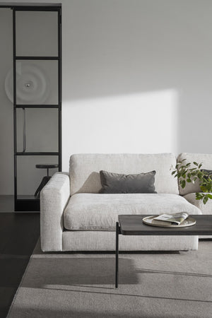 Ljusgrå soffa med grå kudde och soffbord i modern skandinavisk stil med svart hyllsystem