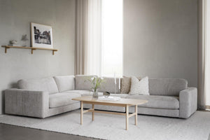Ljusgrå hörnsoffa i vardagsrum med soffbord i trä och minimalistisk inredning