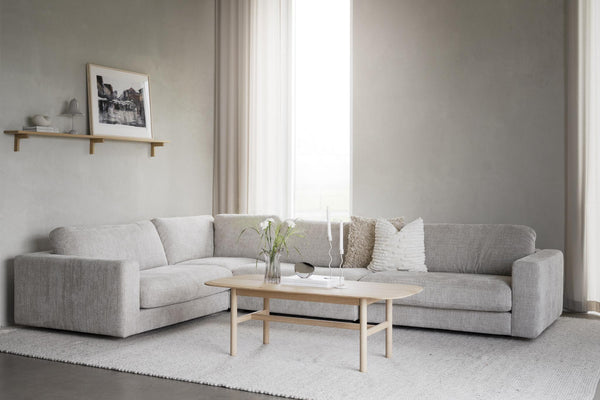Ljusgrå hörnsoffa i vardagsrum med soffbord i trä och minimalistisk inredning