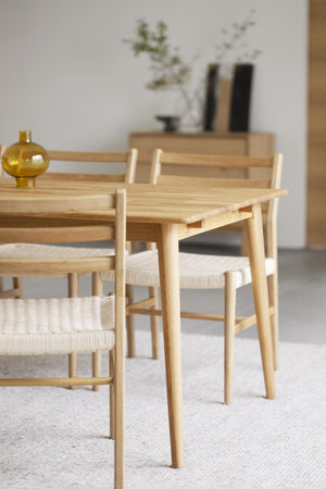 Matbord i ljust trä med tillhörande stolar med flätade sitsar i skandinavisk design