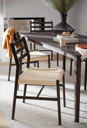 Matstol med svart träram och flätad sits i natur vid matbord med dekorativa föremål