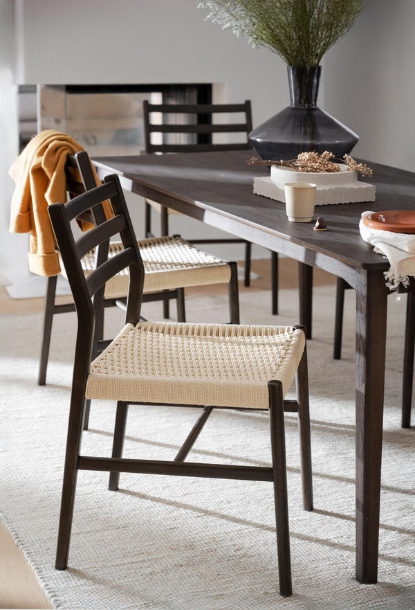 Matstol med svart träram och flätad sits i natur vid matbord med dekorativa föremål