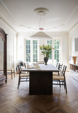 Elegant matsal med mörkt matbord, träflätat stolar, taklampa och franska fönsterdörrar i vitt klassiskt rum