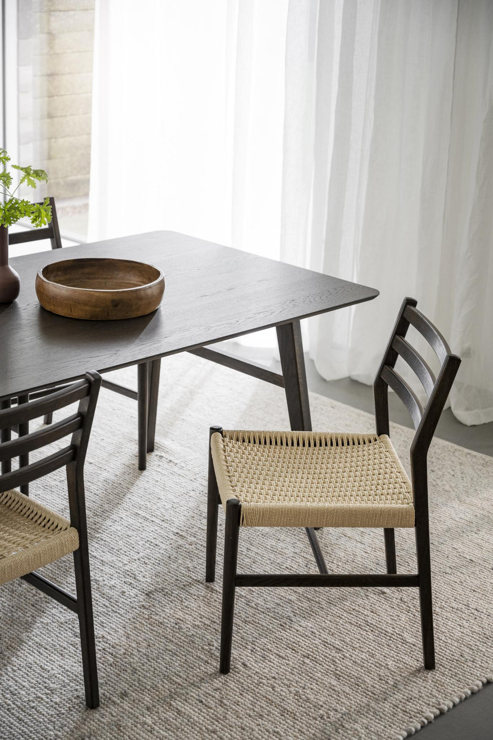Matstol i mörkbrun ek med flätad sits av naturligt rep och enkel skandinavisk design