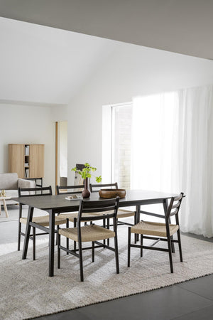 Matgrupp med svarta stolar och rotting sits vid matbord i ljust skandinaviskt matrum