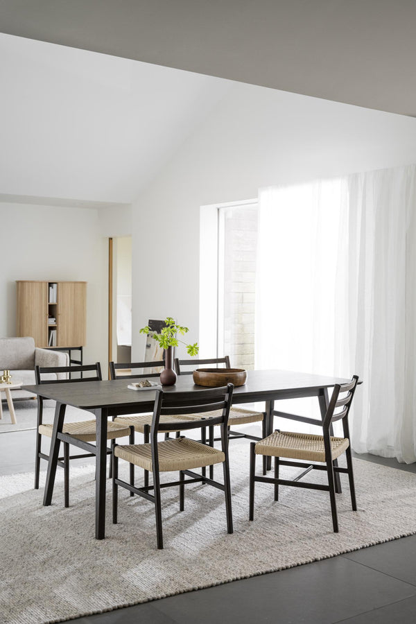 Matgrupp med svarta stolar och rotting sits vid matbord i ljust skandinaviskt matrum
