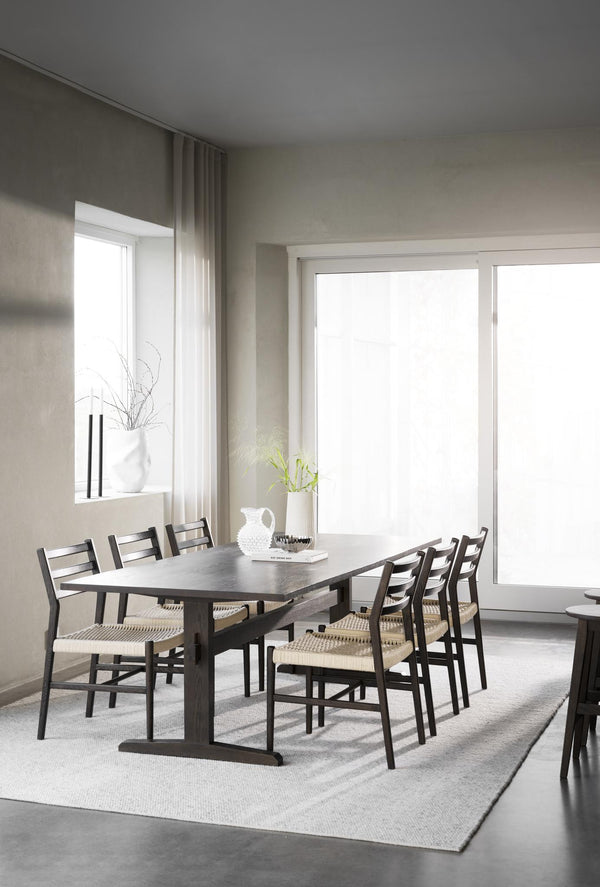 Matbord i mörkt trä med sex stolar i skandinavisk stil i minimalistiskt matrum med stora fönster