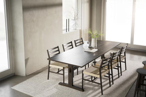 Matgrupp med mörkt träbord och sex stolar med flätade sitsar i ljust matrum med stora fönster