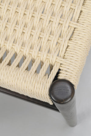 Närbildsdetalj av flätat rep i naturfärg på möbel med mörk träfot