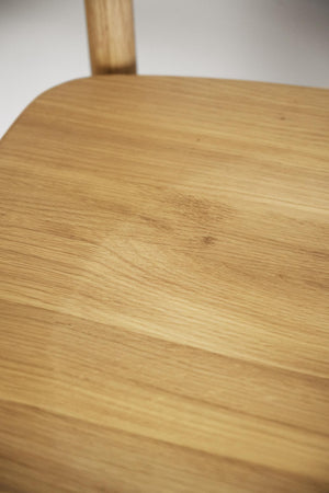 Närbilder på ljust ekträ med synlig struktur och naturlig ådring på stolsits