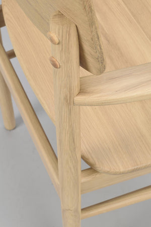 Närbild på stolens träkonstruktion med synliga träpluggförbindelser och naturlig ekfärg