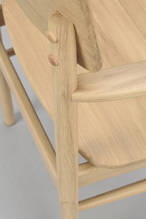 Närbild på stolens träkonstruktion med synliga träpluggförbindelser och naturlig ekfärg