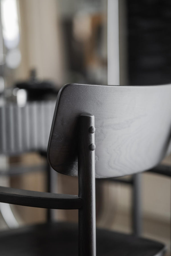 Närbild på svart stol i trä med rundad rygg och elegant design i modern inredning