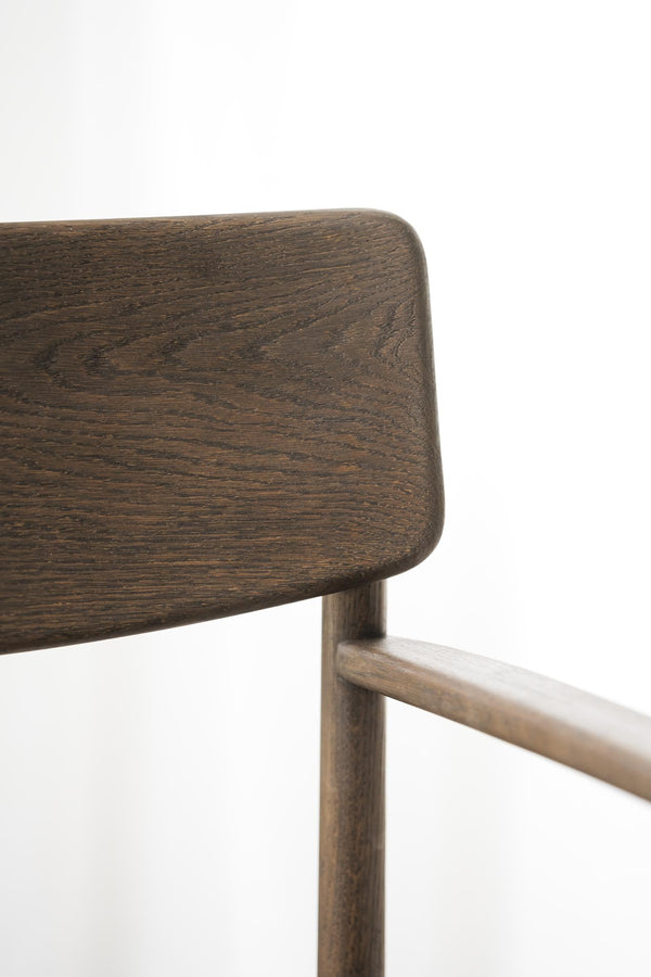 Närbild av mörk ekstol med rundade hörn och naturlig trästruktur, eleganta träben