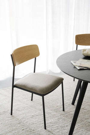 Matstol med ljust trädäck, beige stoppad sits och svarta metallben vid runt matbord