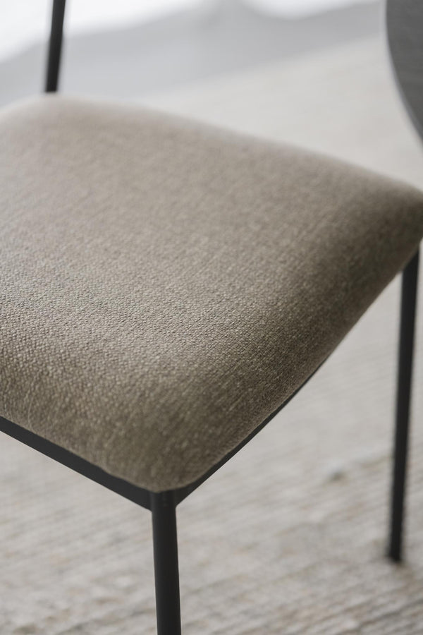 Närbild på grå stoppad sits med svart metallram på modern stol