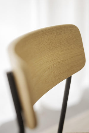 Närbild av stolsrygg i ljust trä med synlig ådringsstruktur och rundade hörn på modern designstol