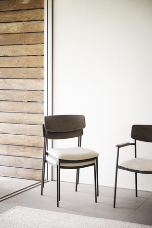Moderna matstolar med svart metallstomme, mörk trärygg och ljus stoppad sits i minimalistisk miljö