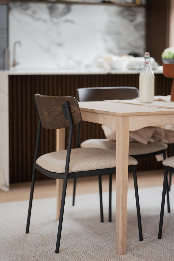 Matbord i ljus ek med moderna stolar med svarta ben och beige sits i skandinavisk matsal