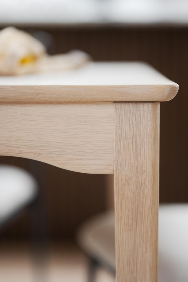 Närbild på hörn av soffbord i ljust trä med rundade kanter och synlig trästruktur