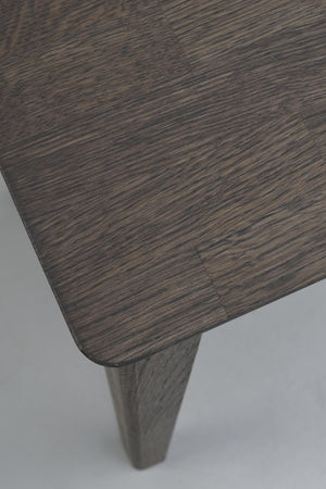 Mörkbrun träbordsskiva med tydlig trästruktur och avsmalnande träben i närbild