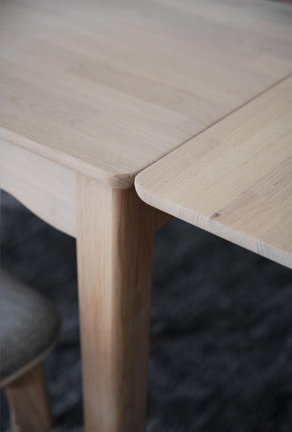 Närbild på hörn av träbord med rundad kant i ljust trä och synlig trästruktur