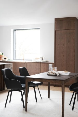 Matbord i mörkt trä med svarta stolar i modern minimalistisk matsal med skåpsinredning