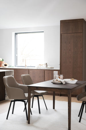 Matbord i mörkt trä med moderna stolar i beige och grå, placerats i ljust kök med matchande skåp