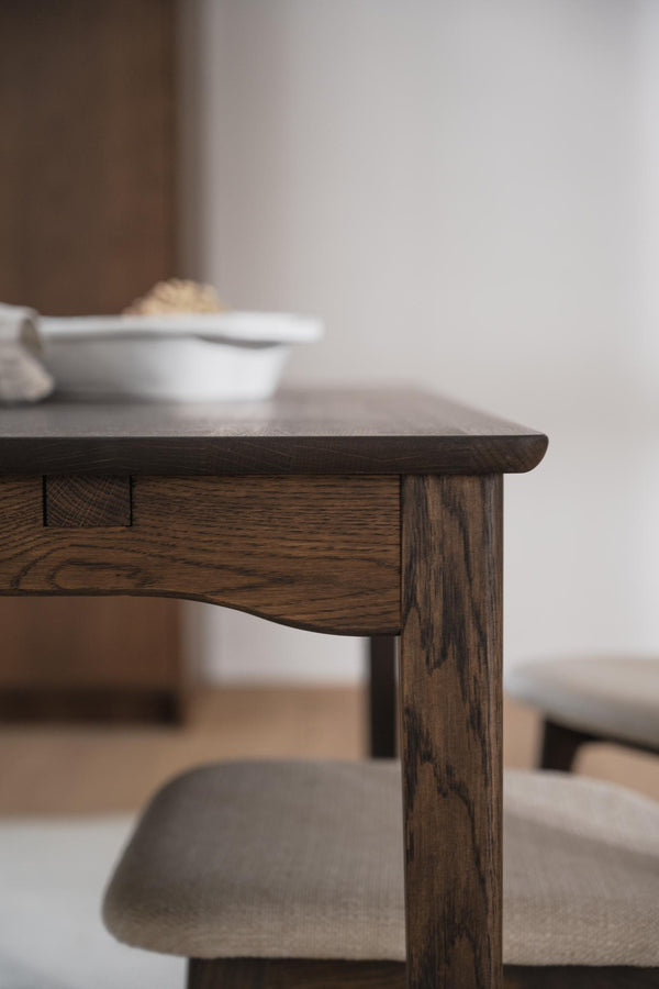 Massivt matbord i mörkt trä med synlig trästruktur och träben, närbild av hörn och detaljer