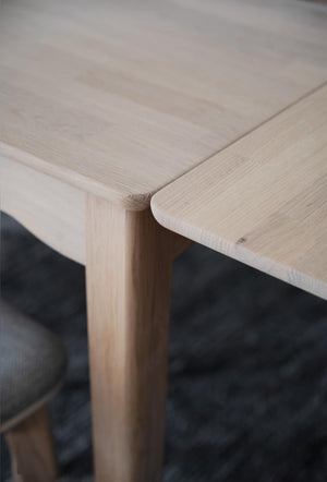 Närbildsdetalj av träbordshörn med rundad kant och synlig trästruktur i ljust trä