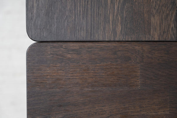 Närbild på mörkt träfanér med synlig struktur och rundade hörn på möbelpaneler