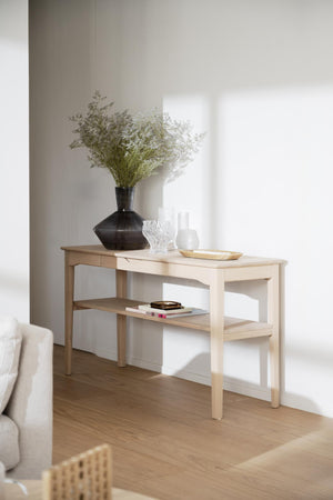 Ljust konsolbord i trä med hylla, dekorerat med vas och accessoarer i minimalistisk skandinavisk stil