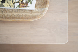 Ljust trä skrivbord med dekorativ stenfat och botanisk print ovanifrån