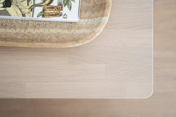 Ljust trä skrivbord med dekorativ stenfat och botanisk print ovanifrån