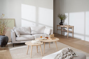 Minimalistiskt vardagsrum med beige soffa, ljusa träbord och skandinavisk inredning i naturliga toner