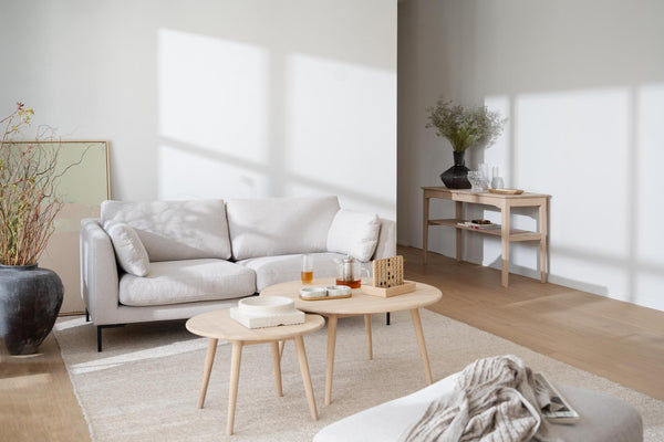 Minimalistiskt vardagsrum med beige soffa, ljusa träbord och skandinavisk inredning i naturliga toner