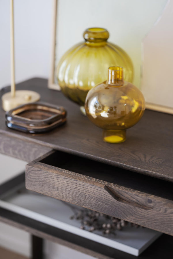 Sideboard med öppen låda och gula glasvaser i olika storlekar som dekoration