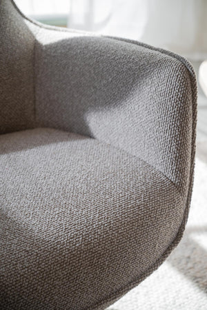 Grå fåtölj med textilfodral i närbild, visar mjuk klädsel och rundade armstöd