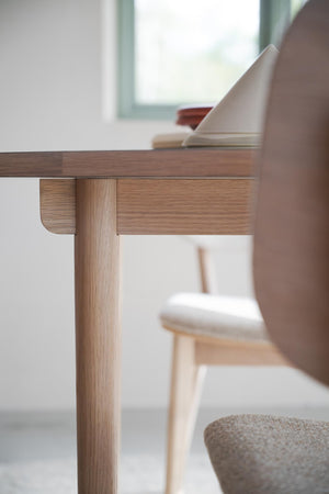 Närbild på massivt ekbord med rundade kanter och träben i skandinavisk design