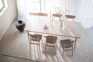 Matbord i ljust trä med sex stolar i skandinavisk design, dekorerat med vas och ljusstakar i minimalistisk matsal